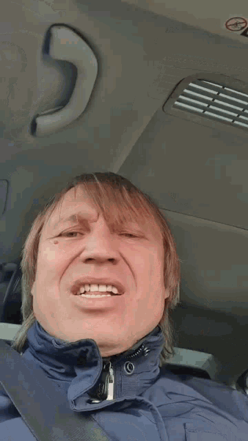 a man in a blue jacket is making a funny face