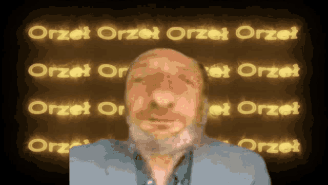a man with a beard is standing in front of a wall that says orzet