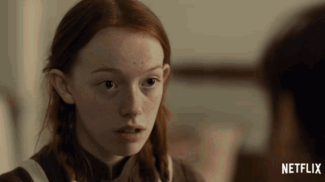 a girl with red hair and freckles is looking at a man with netflix written on the bottom