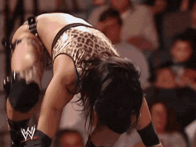 a woman in a leopard print top is bending over with a w logo on her arm .