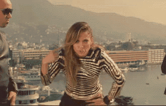 a woman in a striped sweater is standing in front of a man in sunglasses .