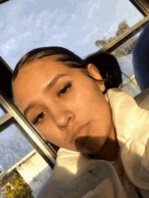 a young girl is taking a selfie in front of a window while sitting on a bus .