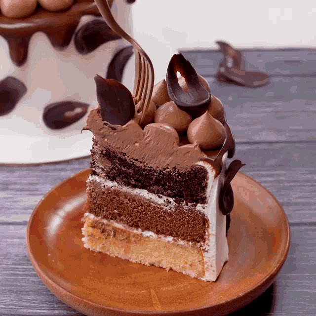 a slice of chocolate cake on a wooden plate with a cake in the background