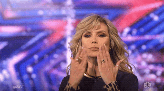 a woman is making a funny face with her hands while standing on a stage .