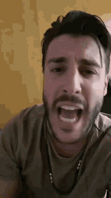 a man with a beard is making a funny face with his mouth wide open .