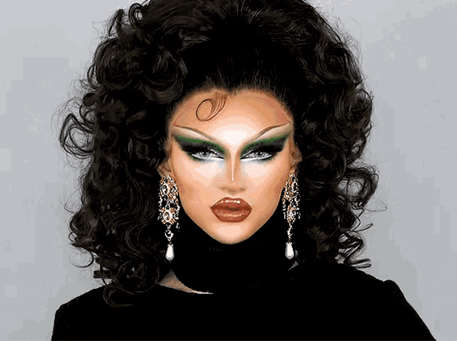 a close up of a drag queen 's face with a turtleneck and earrings