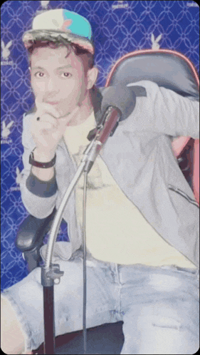 a man sitting in a chair with a microphone and a hat that says adidas on it