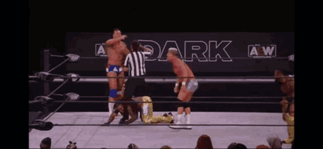 a group of men are wrestling in a wrestling ring with a sign that says dark on it .