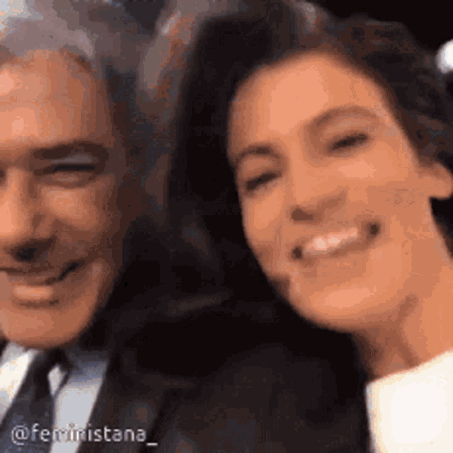 a man and woman are posing for a picture and smiling for the camera .