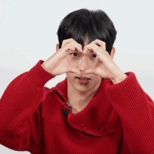 a man in a red sweater is making a heart with his hands