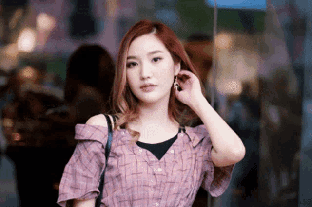 a woman with red hair is wearing a plaid shirt and black tank top