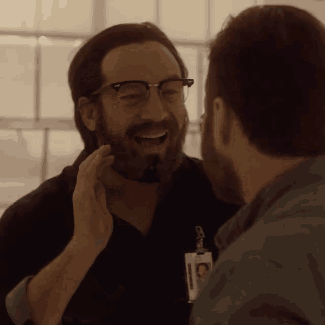 a man with glasses and a name tag that says ' chris ' on it is laughing with another man
