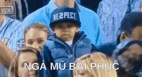 a boy wearing a hat that says respect is sitting in a crowd of people .