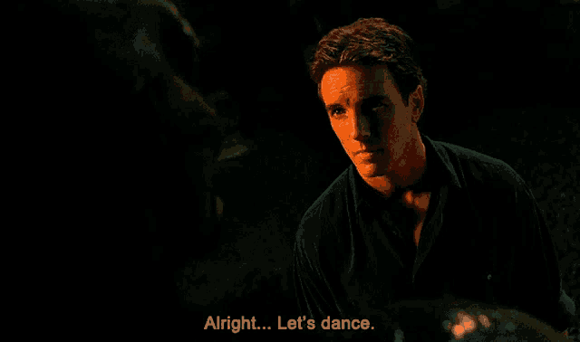 a man says " alright let 's dance " in a dark scene