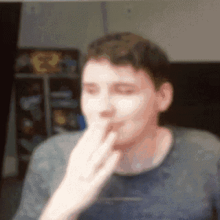 a man is covering his mouth with his hand while looking at the camera .