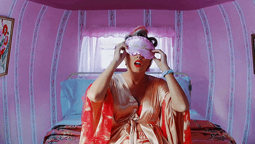 a woman wearing a pink sleep mask that says princess