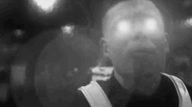 a black and white photo of a man 's face with his eyes glowing .