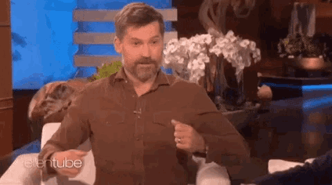 a man with a beard is sitting on a couch in front of an ellentube sign