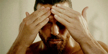 a shirtless man covering his eyes with his hands