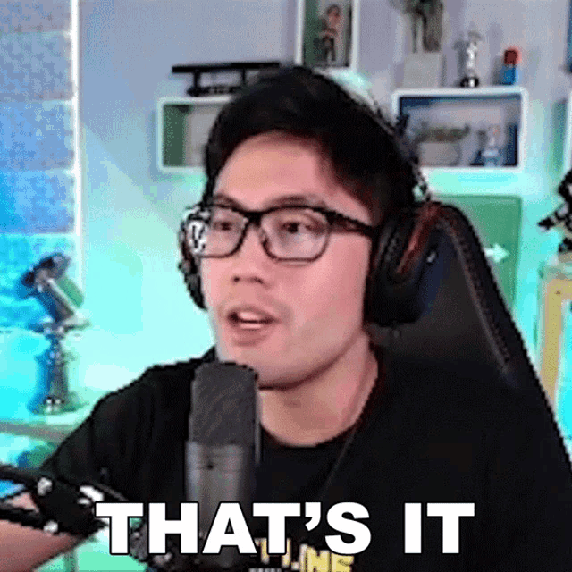 a man wearing headphones and glasses says that 's it in front of a microphone