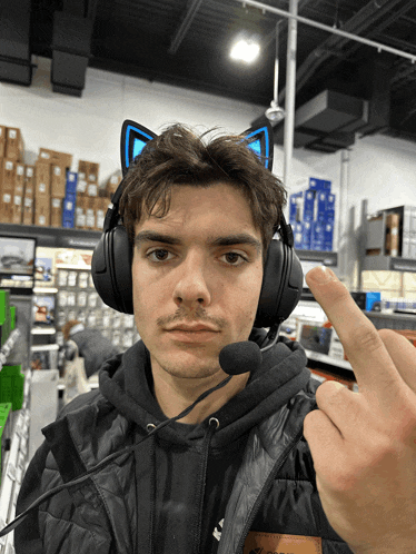 a man wearing a cat ear headset with a microphone giving the middle finger