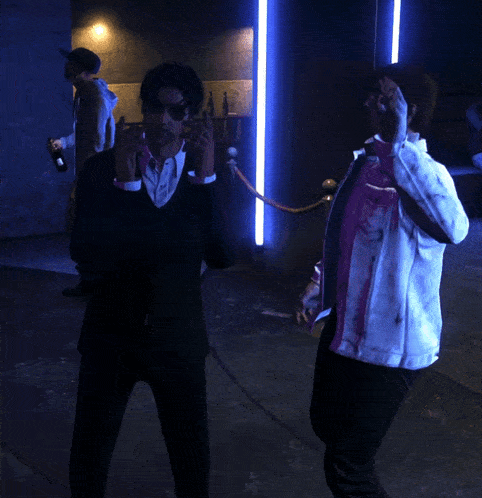 a man in a bloody jacket is standing next to another man in a black suit