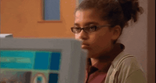 a woman wearing glasses looks at a computer monitor with a blue screen