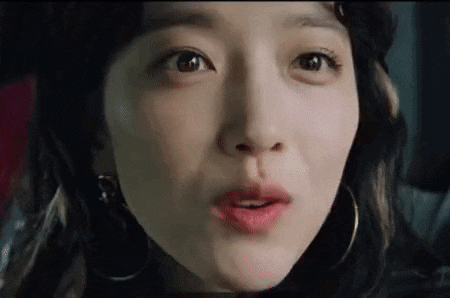 a close up of a woman 's face with her mouth open and earrings on .