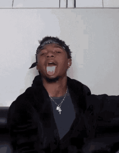 a young man with a bandana on his head is sticking his tongue out .