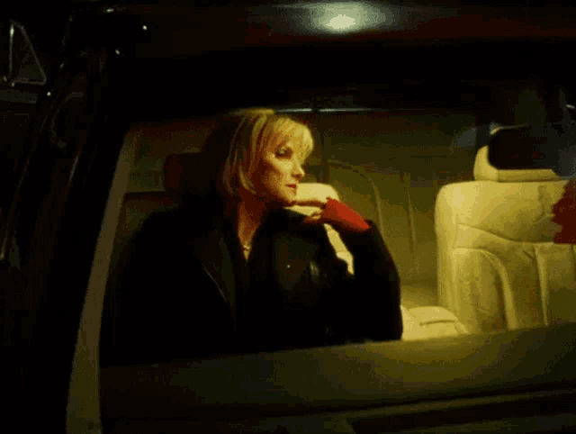 a woman is sitting in the back seat of a car and looking out the window