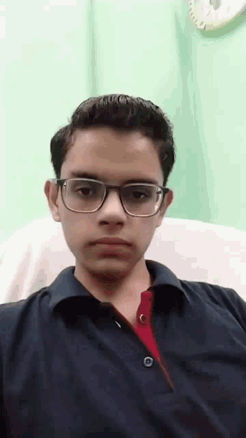 a young man wearing glasses and a black shirt is sitting in a chair