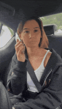 a woman sitting in the back seat of a car talking on her phone