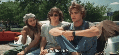a group of young men are sitting on the back of a car and one of them is saying go like this .