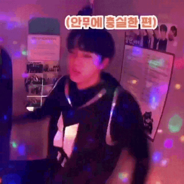 a man is standing in front of a wall with a poster on it that says ' korean ' on it .