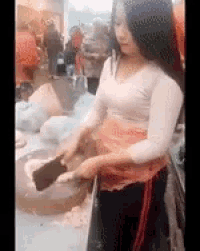 a woman is standing in front of a table holding a spatula and a bowl of food .