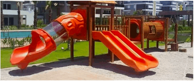 a playground with an orange slide and a red tunnel