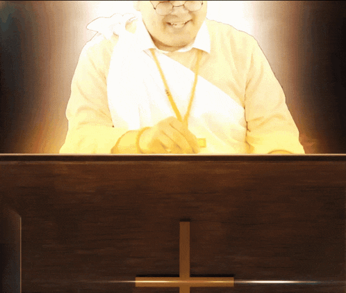 a man stands behind a wooden podium with a cross in front of him