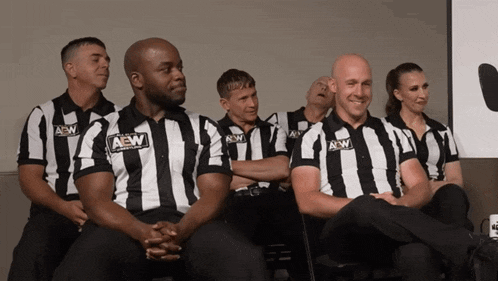 a group of men wearing aew striped shirts sit in a row