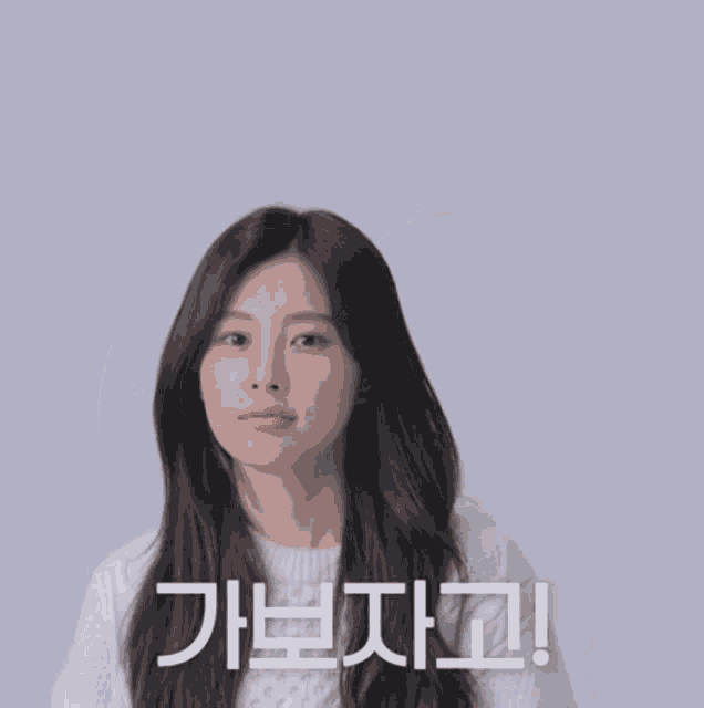 a woman in a white sweater holds her fist up in the air in front of a sign that says " i love you "