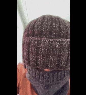 a person wearing a knitted hat and a scarf around their neck