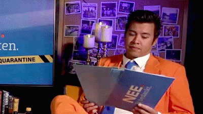 a man in an orange suit is reading a book with nee written on it
