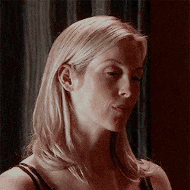 a close up of a woman 's face with blonde hair and a black tank top