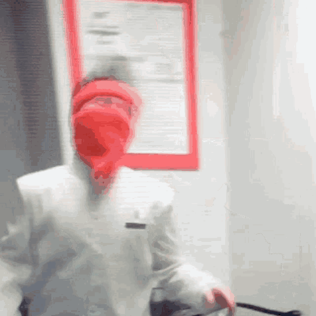 a person wearing a red mask is standing in front of a red sign .