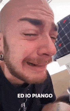 a bald man with a beard is crying and making a funny face with his eyes closed .