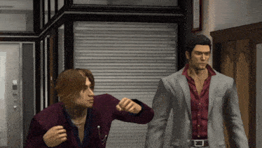 a man in a suit and a man in a red shirt are standing in a hallway