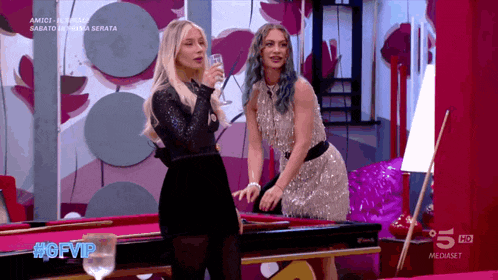 two women standing next to a pool table with the hashtag #gfvip on the bottom
