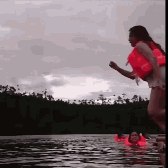 a woman in an orange life jacket is standing in the water