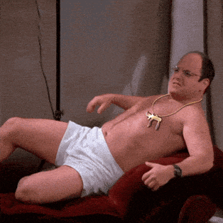 a shirtless man laying on a couch with a necklace of keys on his chest