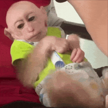a baby monkey wearing a green shirt is playing with a bottle