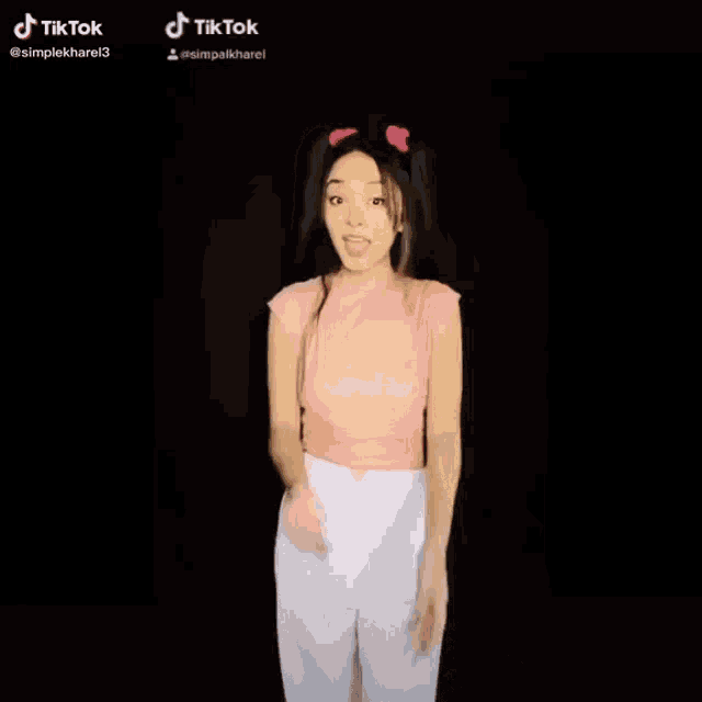 a girl in a pink top and white pants is standing in front of a black background